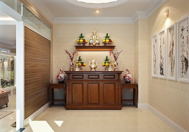 Phòng thờ với bàn thờ gỗ, trang trí hoa quả, tượng và tranh treo tường thanh nhã, tạo không gian trang nghiêm.