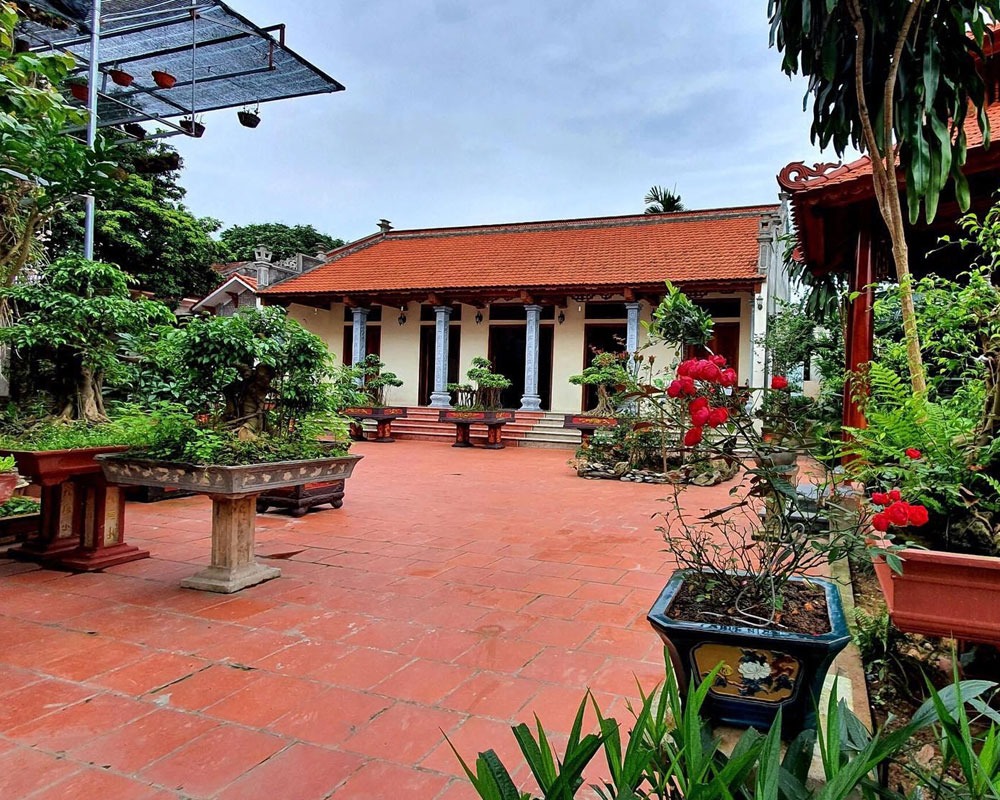 Nhà ngói truyền thống Việt Nam với sân gạch đỏ và cây cảnh xanh tươi, mang nét văn hóa cổ kính.