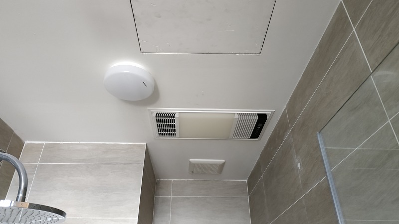 Trần phòng tắm với quạt thông gió và đèn, gạch lát màu xám, thiết kế hiện đại.