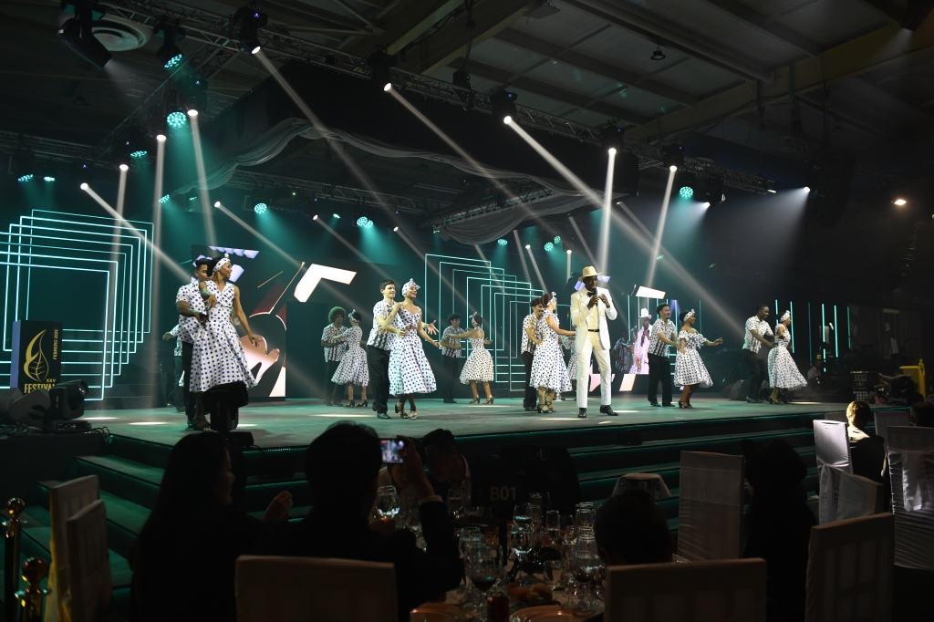 a851478-1 Nhóm múa biểu diễn trên sân khấu với ánh đèn chiếu sáng và trang phục chấm bi tại sự kiện.