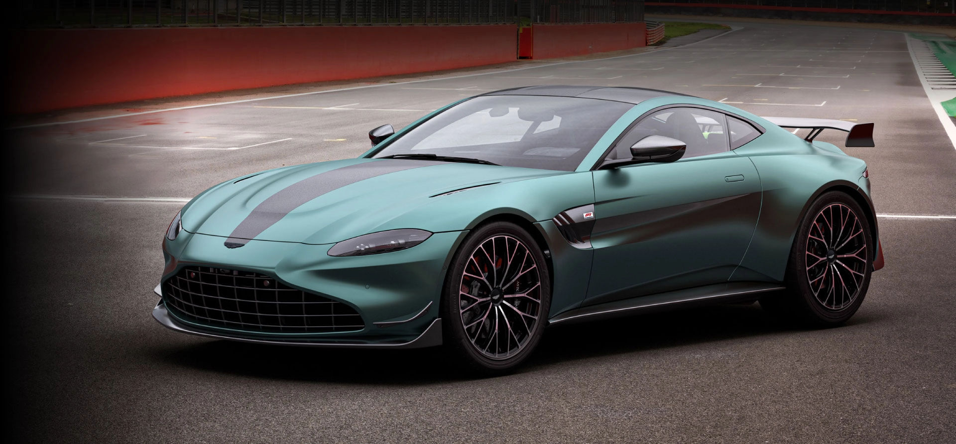 aston-martin-vantage-f1-edition-desktop Xe thể thao màu xanh lục đậm, thiết kế hiện đại trên đường đua, nổi bật với bánh xe hợp kim lớn.