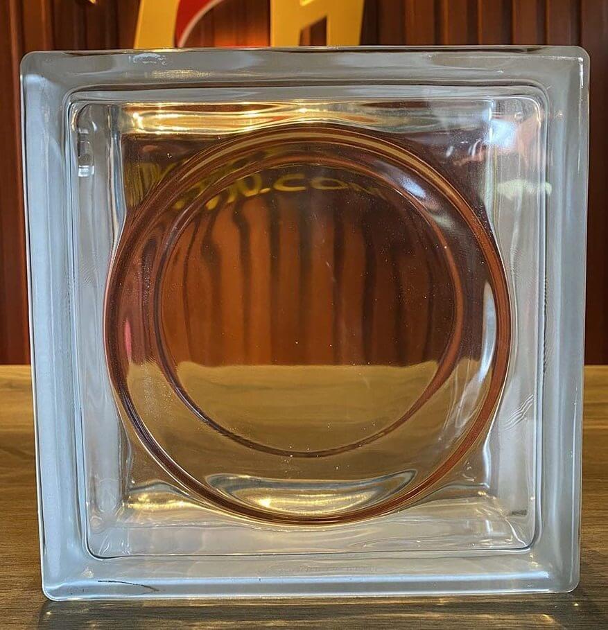 Khối thủy tinh trong suốt hình vuông với viền tròn nổi bật, phông nền gỗ nâu.