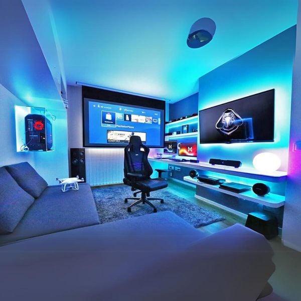Phòng chơi game hiện đại với ánh sáng LED xanh, ghế gaming và màn hình lớn.