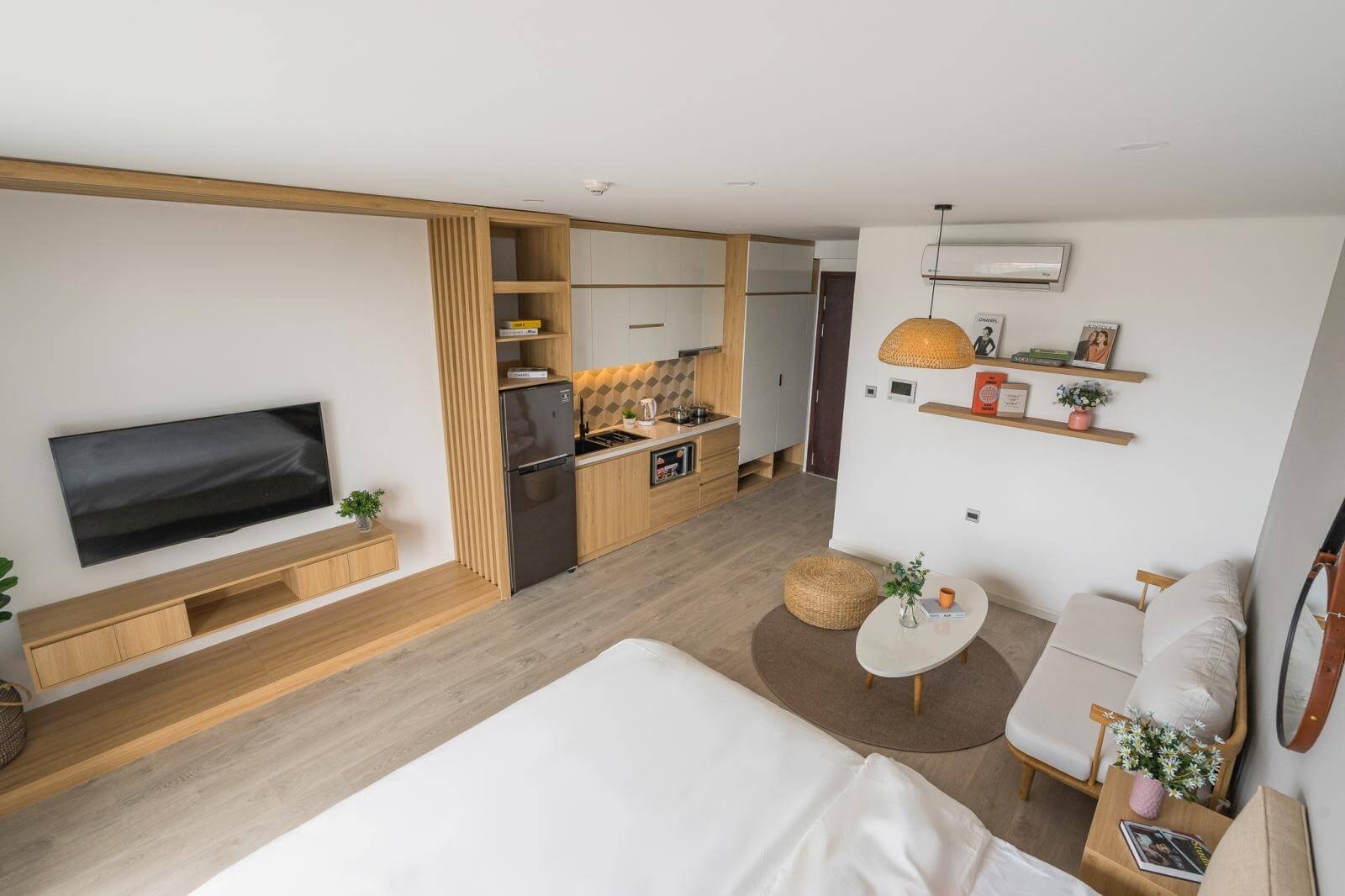 Căn hộ nhỏ gọn với phòng khách, bếp hiện đại, nội thất gỗ, tivi treo tường và bàn trà trang nhã.