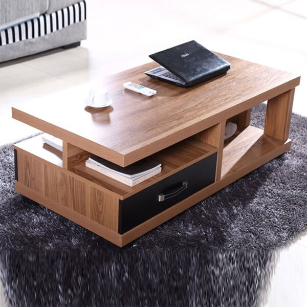 Bàn trà gỗ hiện đại với laptop và sách, thiết kế có ngăn kéo đặt trên thảm xám.