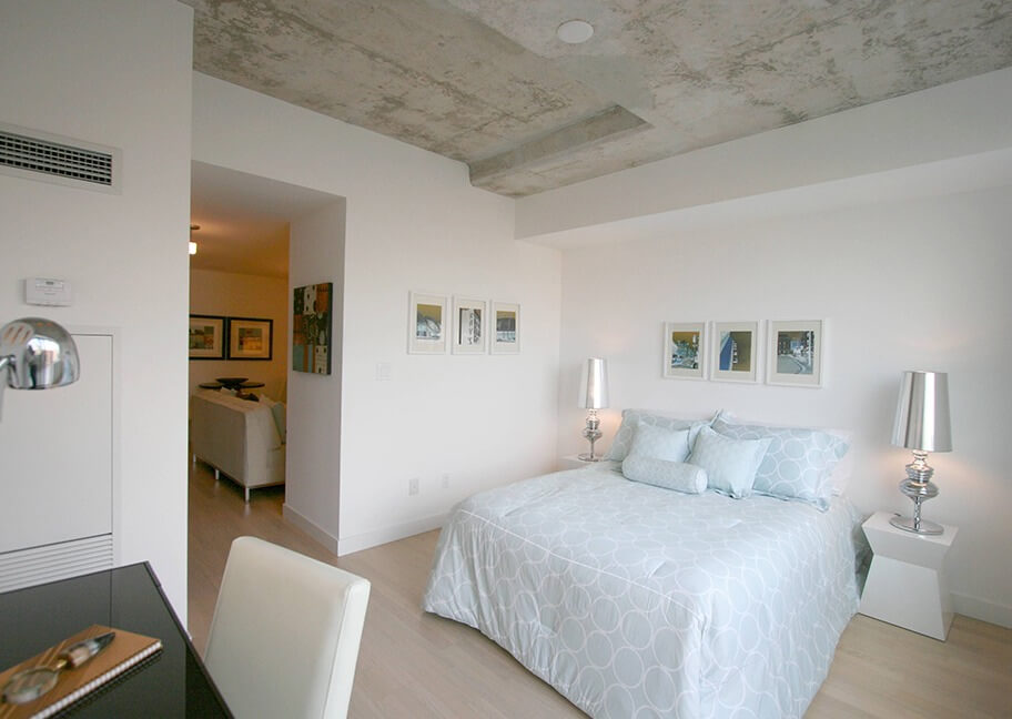 Phòng ngủ hiện đại với trần bê tông, giường đôi và trang trí tranh treo tường.