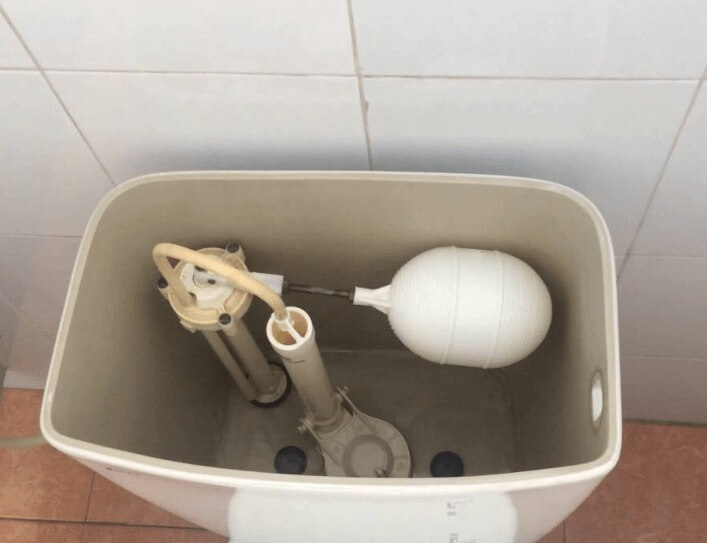 Bên trong bồn chứa nước bồn cầu với hệ thống phao và van xả.