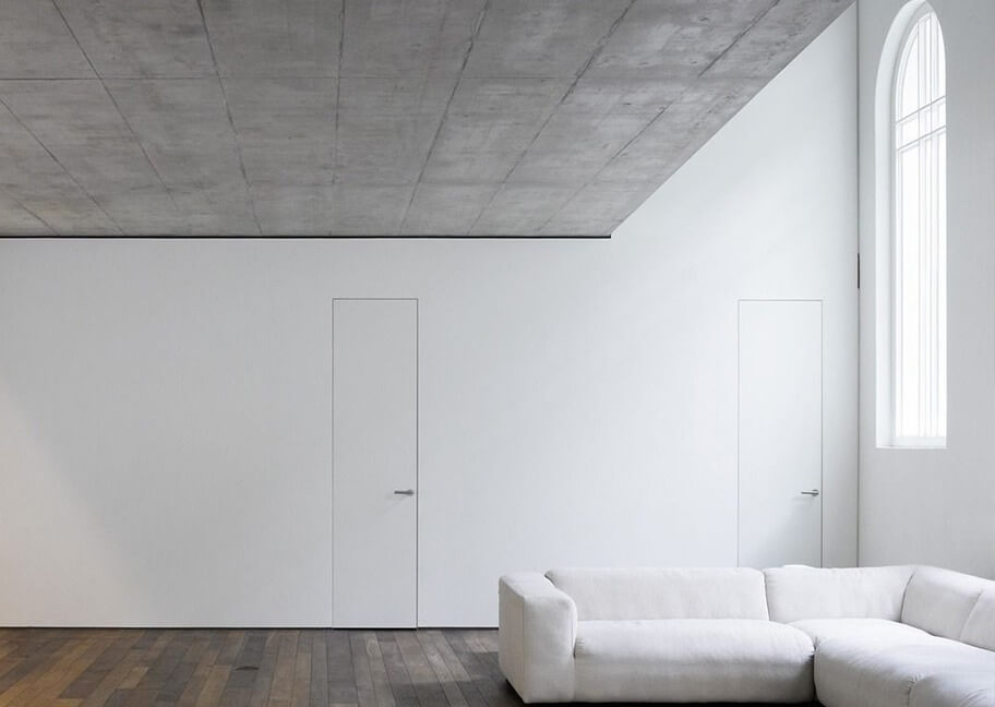 Phòng khách tối giản với tường trắng, ghế sofa trắng và cửa sổ cao.