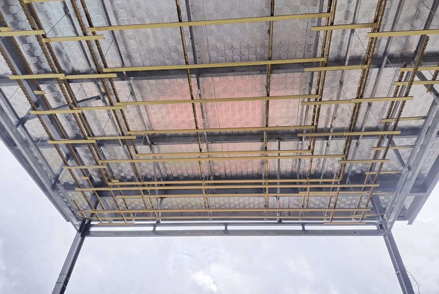 cac-buoc-thi-cong-tran-thach-cao-cong-3 Khung mái nhà từ dưới nhìn lên với cấu trúc thép và nhôm, nền trời xanh mây trắng.