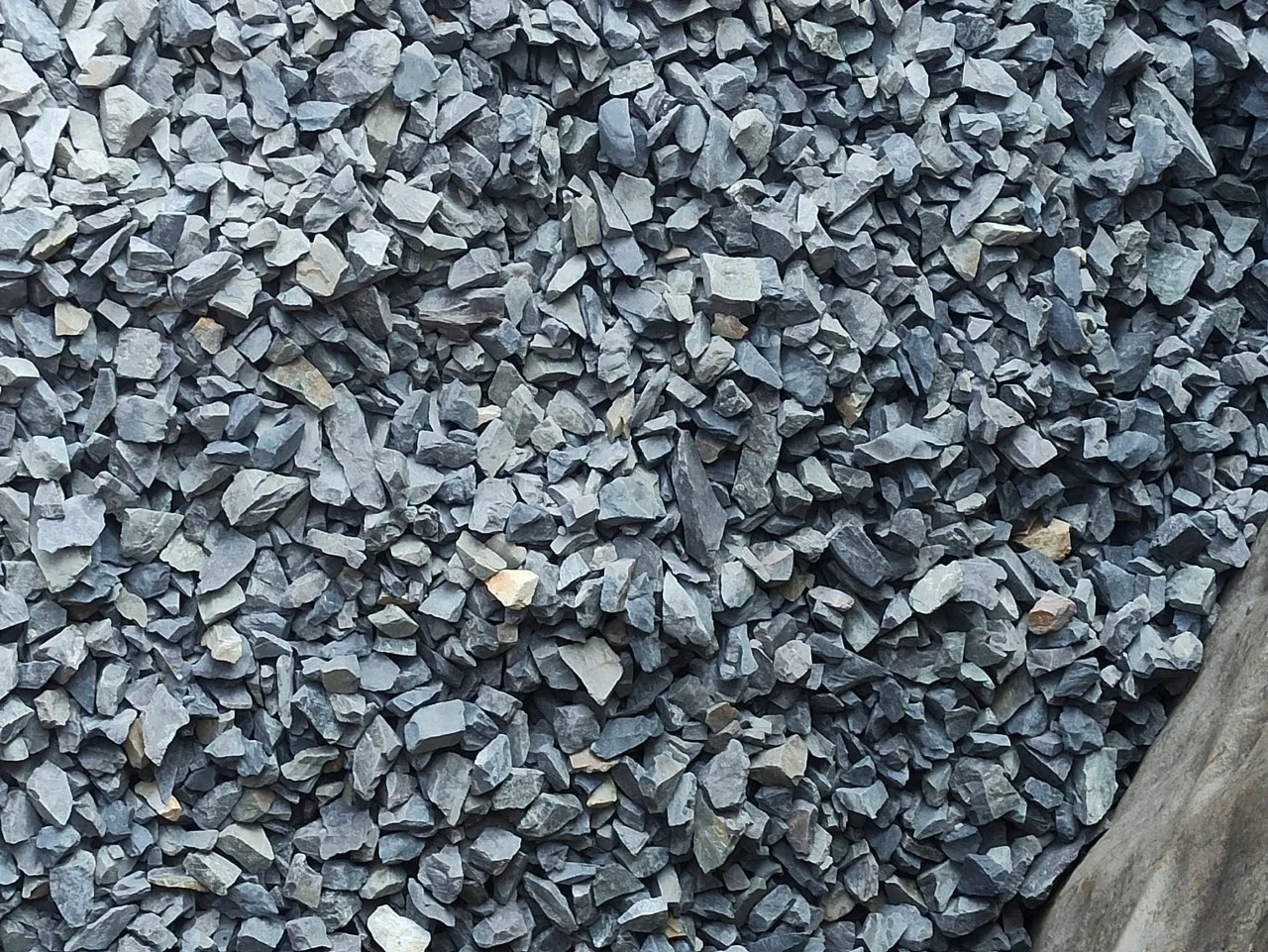 Đống sỏi xanh xám dùng trong xây dựng trên nền đất, phù hợp cho trang trí sân vườn và làm đường.