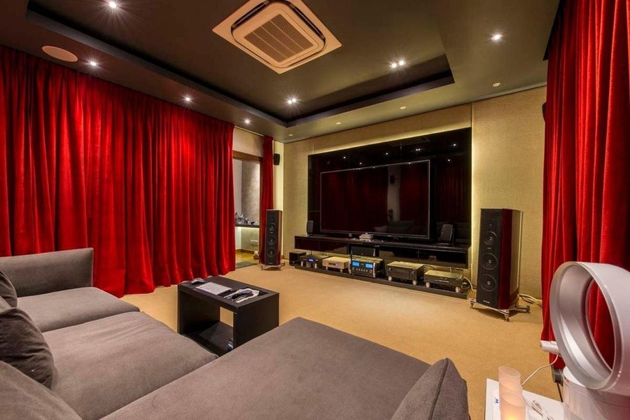 cac-yeu-to-can-xem-xet-khi-thiet-ke-phong-giai-tri-tai-nha Phòng chiếu phim tại gia sang trọng với rèm đỏ, sofa thoải mái và màn hình lớn.