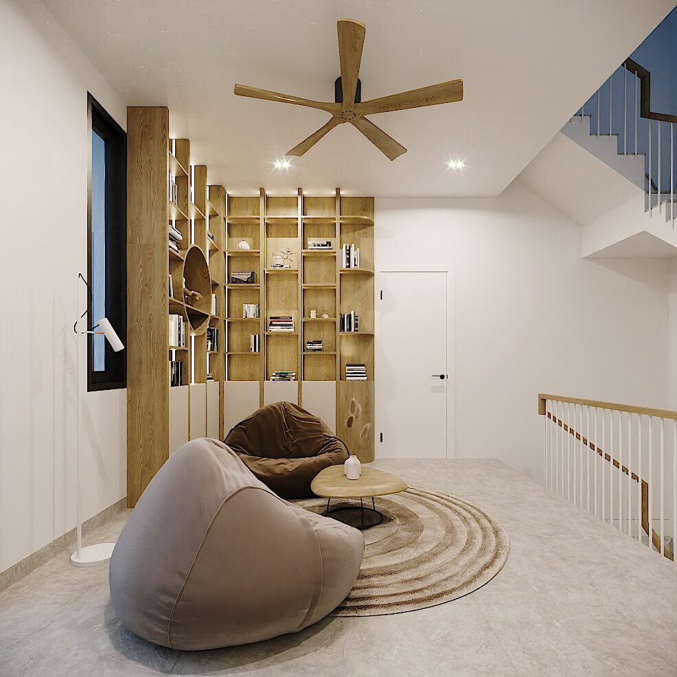 Ghế lười và bàn tròn trong phòng khách hiện đại với kệ sách gỗ, quạt trần, và cầu thang.