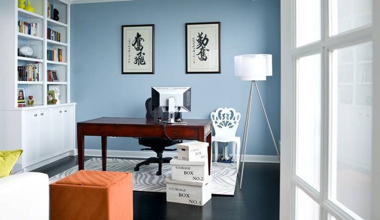 Phòng làm việc tại nhà phong cách hiện đại với tường xanh, bàn gỗ, và sách trên kệ trắng.