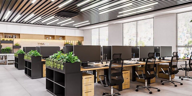 Văn phòng hiện đại có không gian mở, nhiều máy tính, ánh sáng tự nhiên, và cây xanh trang trí.