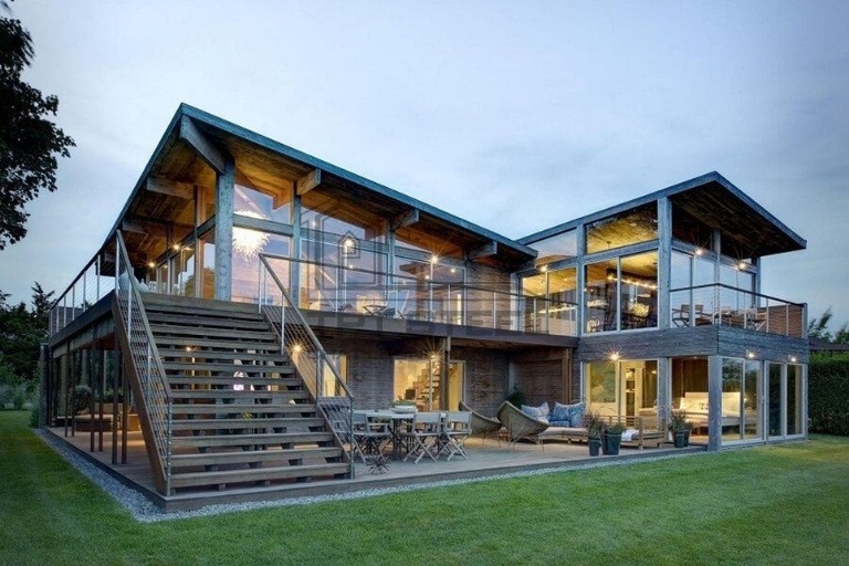 Ngôi nhà hiện đại với kiến trúc kính, thiết kế mở và sân vườn rộng rãi vào buổi tối.