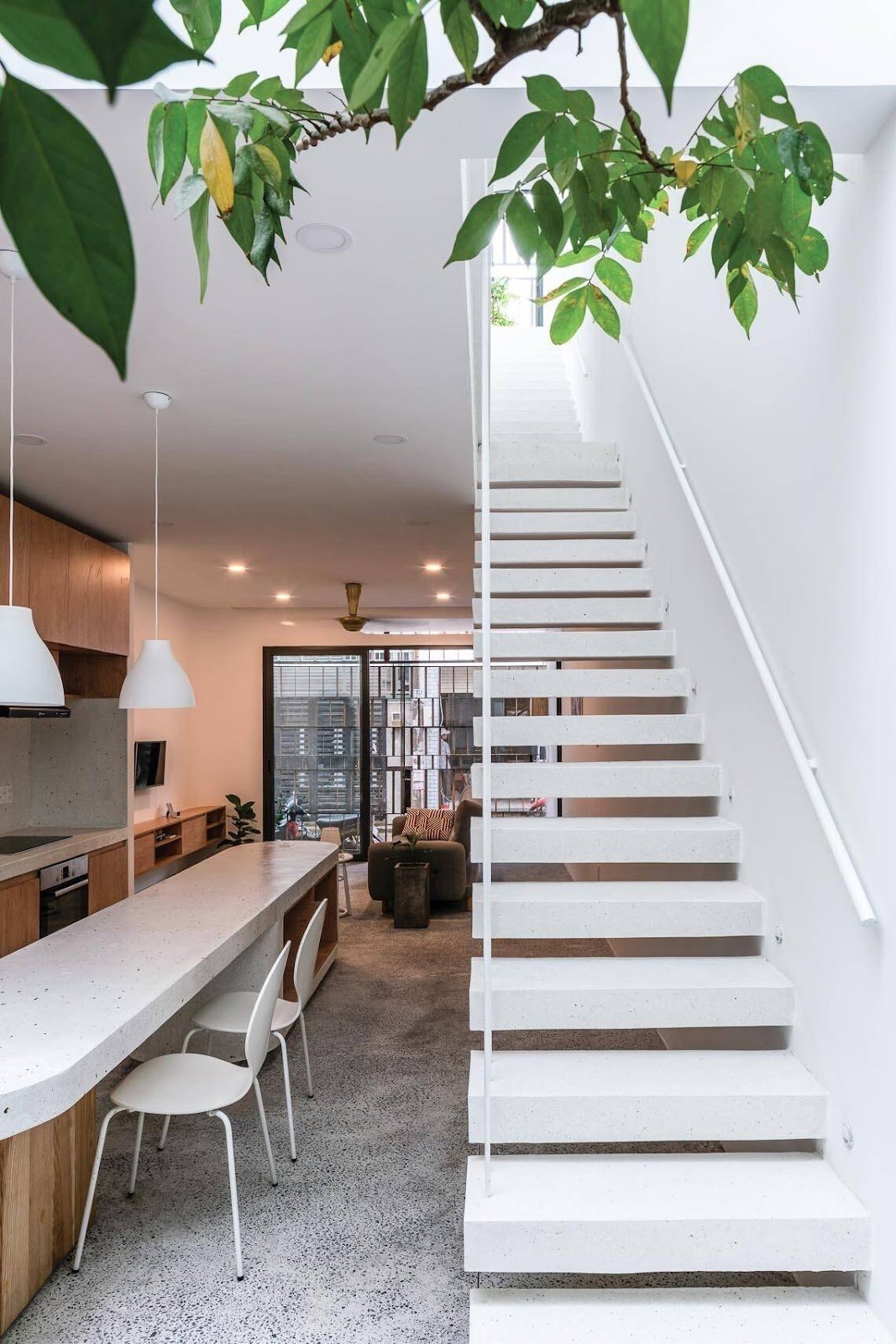 cau-thang-be-tong-cot-thep-lap-ghep Nhà bếp hiện đại với cầu thang trắng và cây xanh phía trên, thiết kế tối giản và sang trọng.