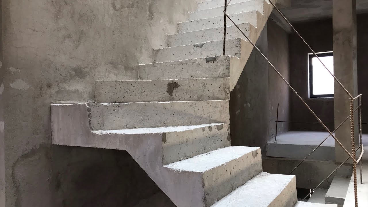 cau-thang-be-tong-cot-thep-toan-khoi Cầu thang bê tông trong tòa nhà đang xây dựng, ánh sáng từ cửa sổ chiếu vào bức tường thô.