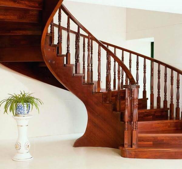 Cầu thang gỗ xoắn hiện đại với thiết kế tinh tế, bên cạnh chậu cây trang trí, tạo không gian sang trọng cho ngôi nhà.