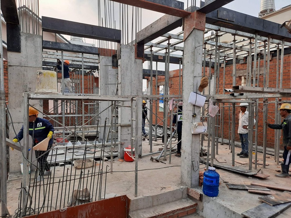 Công nhân xây dựng đang làm việc trên công trường, lắp đặt khung thép và bê tông.