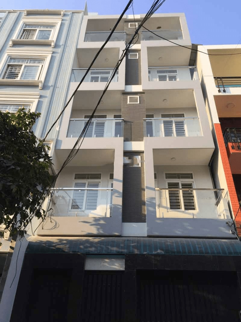 Tòa nhà hiện đại 4 tầng với ban công kính nằm giữa hai công trình khác nhau.