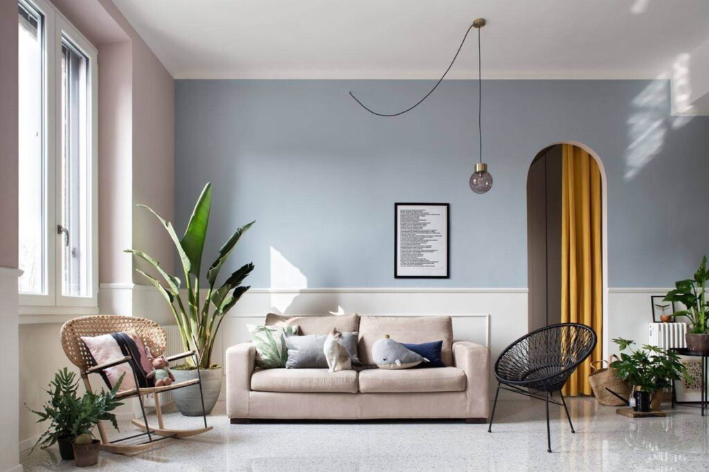 Phòng khách hiện đại với ghế sofa be, cây xanh và đèn treo, tạo không gian thoải mái và thanh lịch.