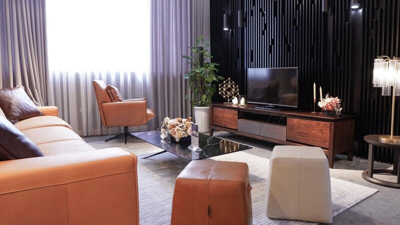 chon-ke-tivi-cho-phong-khach-2 Phòng khách hiện đại với nội thất da nâu, bàn kính, TV và cây cảnh. Ánh sáng tự nhiên từ cửa sổ lớn.