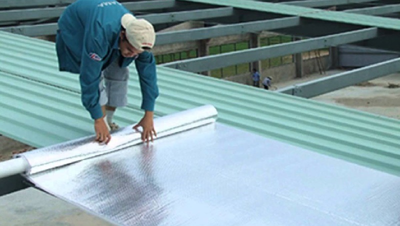 Công nhân lắp đặt tấm cách nhiệt trên mái tôn cho công trình xây dựng.