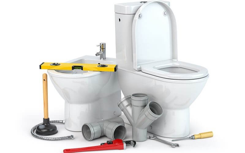 Bồn cầu và dụng cụ sửa ống nước gồm ống, cờ lê, thăng bằng, trong phòng tắm trắng sạch sẽ.