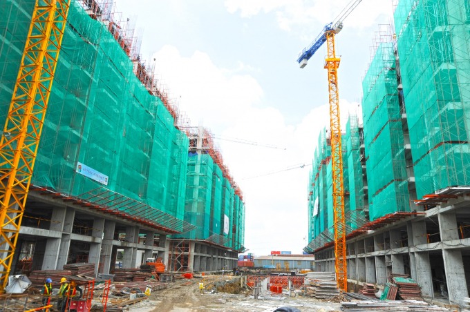 Công trình xây dựng khu đô thị với cần cẩu và giàn giáo xanh tại Việt Nam, trời trong xanh.