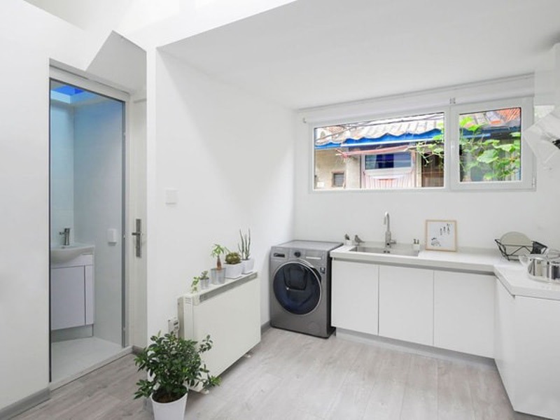 Phòng bếp hiện đại với máy giặt, cây cảnh và cửa sổ lớn nhìn ra ngoài.