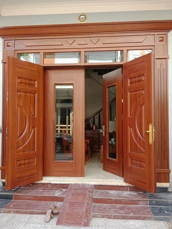 Cửa gỗ hai cánh mở rộng, thiết kế tinh tế, dẫn vào ngôi nhà hiện đại với ánh sáng tự nhiên.