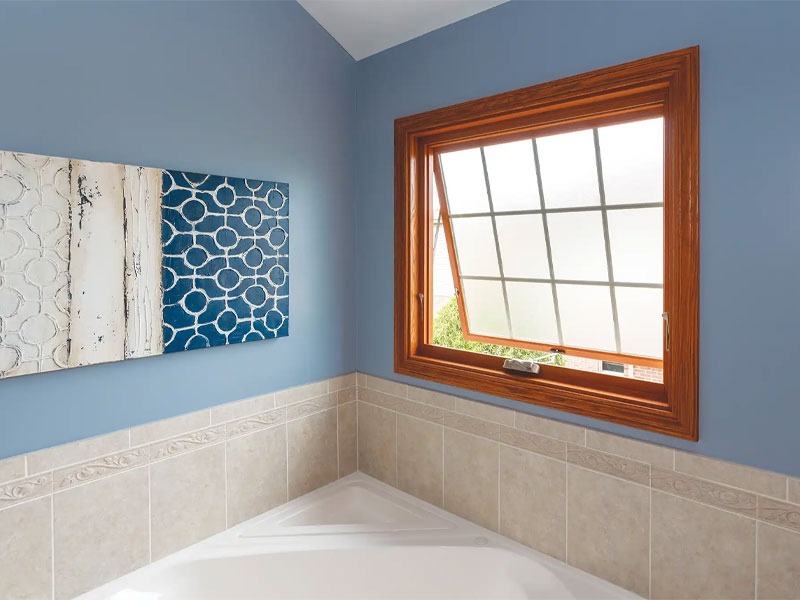 Phòng tắm màu xanh biển với tranh treo tường và cửa sổ kính mở, tạo không gian thoáng đãng.