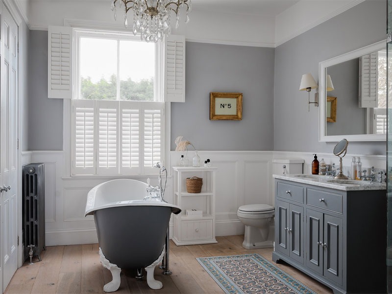 Phòng tắm sang trọng với bồn tắm cổ điển, nội thất màu xám trắng và gương lớn.