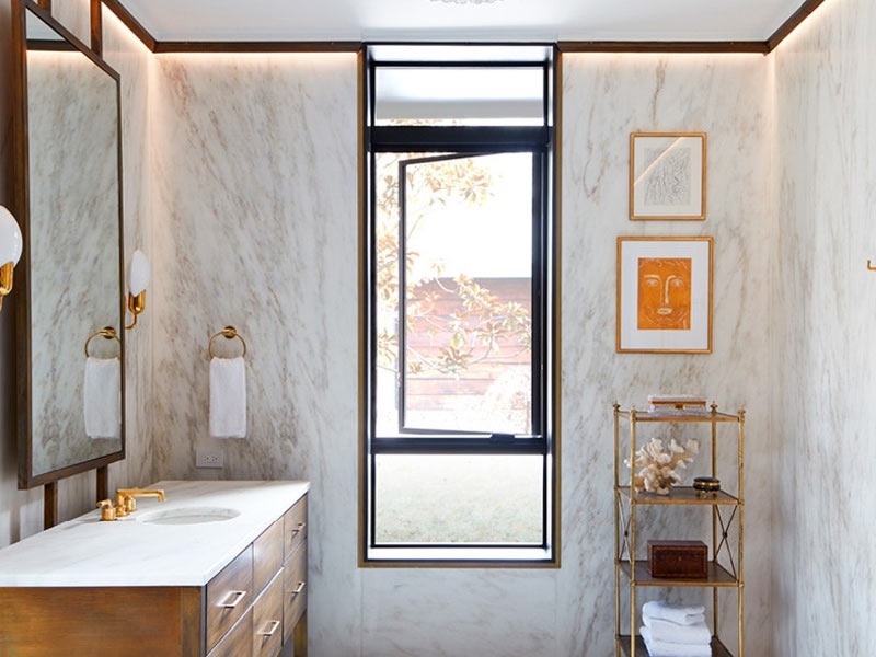 Phòng tắm hiện đại với tường đá cẩm thạch, kệ gỗ và cửa sổ lớn. Thiết kế tinh tế và sang trọng.