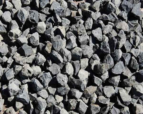 Những viên đá sỏi màu xám đen, kích thước nhỏ, được xếp chồng lên nhau một cách ngẫu nhiên trên mặt đất.