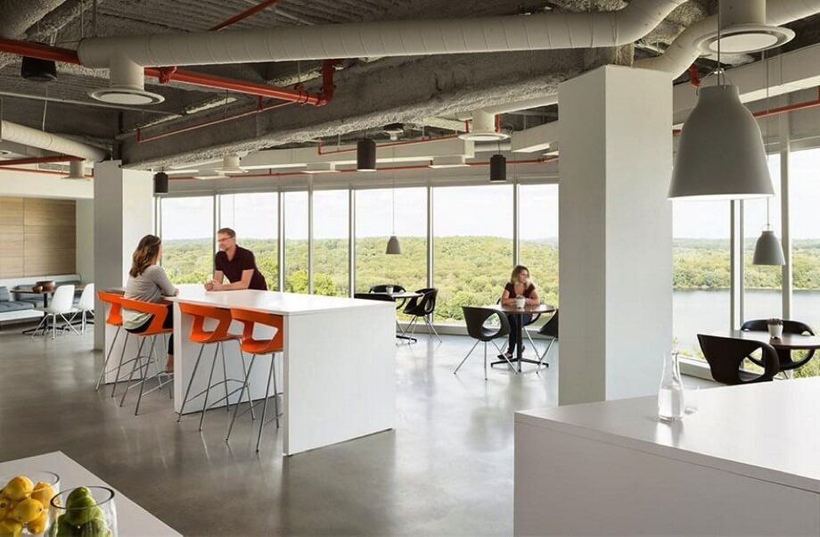 dac-diem-cua-thiet-ke-van-phong-mo-1 Văn phòng hiện đại với cửa sổ lớn, người làm việc và trò chuyện trên các bàn ghế màu sắc.