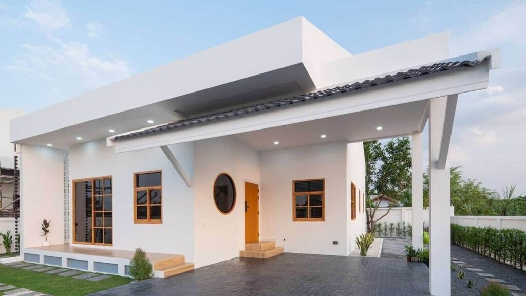 Nhà một tầng hiện đại với mái hiên rộng và cửa sổ lớn, sơn màu trắng, nằm giữa không gian xanh.