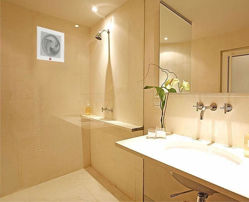 dam-bao-he-thong-thong-gio-cho-nha-tam-nho Phòng tắm sang trọng với bồn rửa mặt, vòi hoa sen và quạt thông gió trên tường, ánh sáng dịu nhẹ.