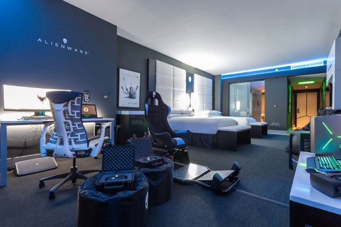 Phòng game hiện đại với thiết bị máy tính cao cấp và ghế game, ánh sáng LED xanh nổi bật.