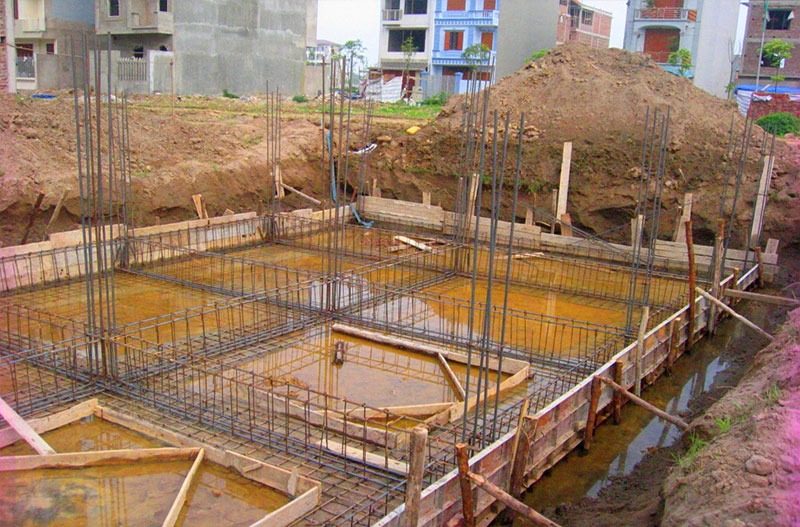 do-mong-nha-ngay-mua-2 Công trường xây dựng móng bê tông cốt thép đang thi công tại khu dân cư, với cốt thép và ván khuôn.