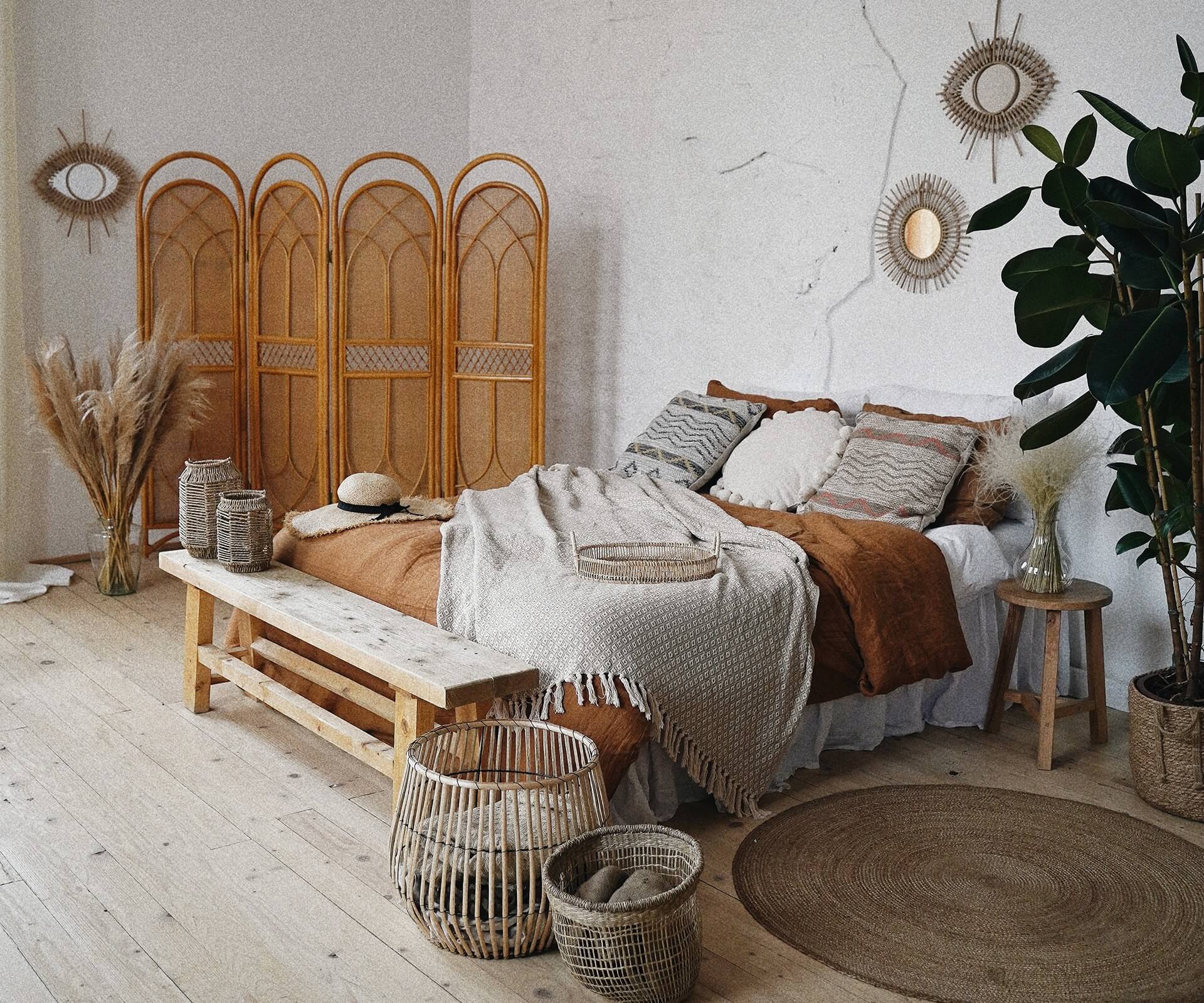 Phòng ngủ phong cách Boho với chăn gối nâu và trang trí từ mây tre đan, cây xanh tạo không gian ấm cúng và hiện đại.