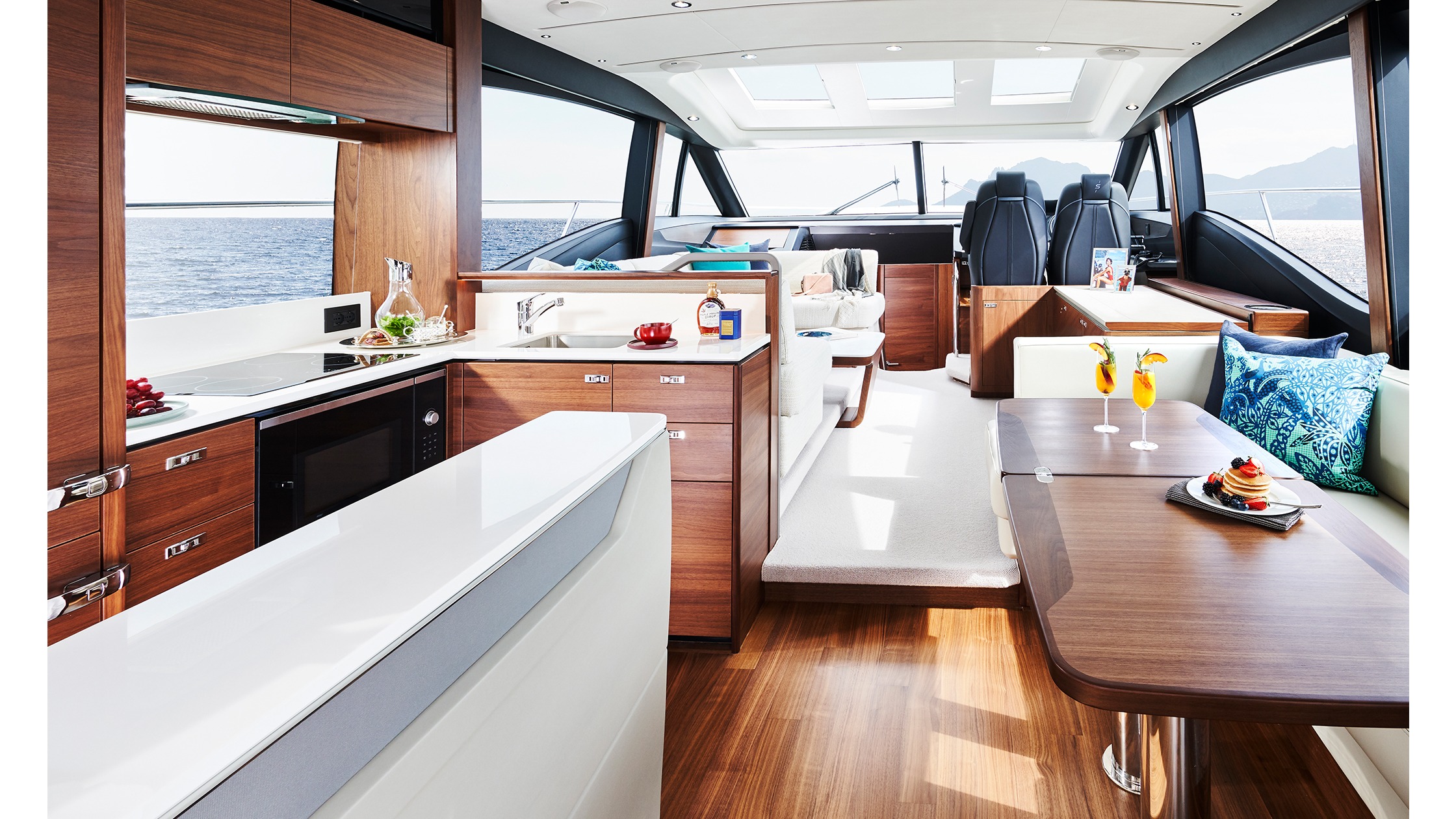 du-th Nội thất sang trọng trên du thuyền với bếp, bàn gỗ và cảnh biển tuyệt đẹp qua cửa sổ lớn.
