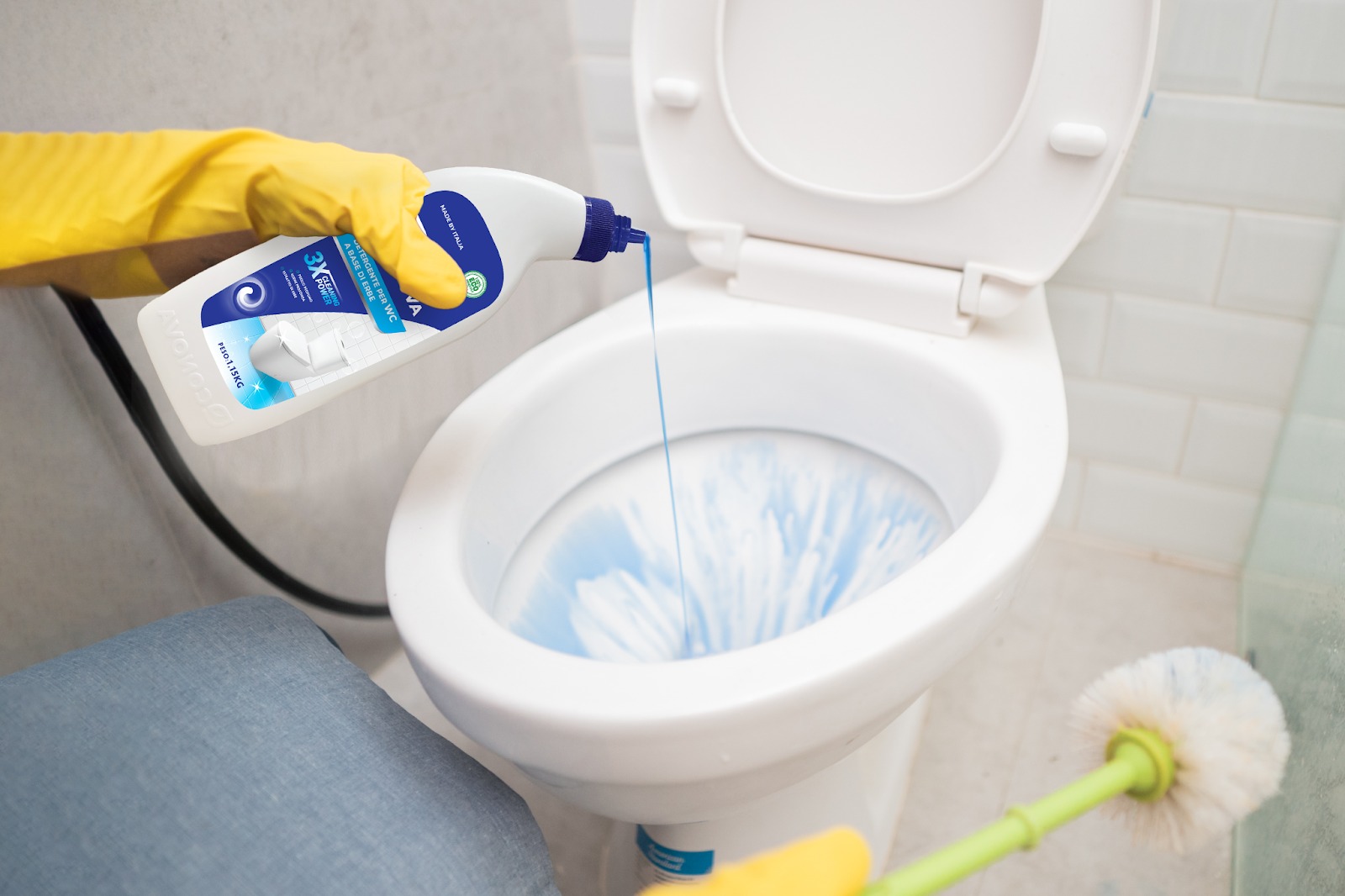 dung-dung-dich-sat-khuan-tay-nap-bon-cau-bi-vang Người đeo găng tay vàng đang đổ chất tẩy bồn cầu màu xanh vào toilet trắng.