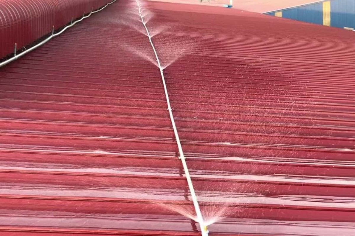 Hệ thống phun nước làm mát trên mái tôn đỏ nhằm giảm nhiệt độ nhà xưởng ngày hè.