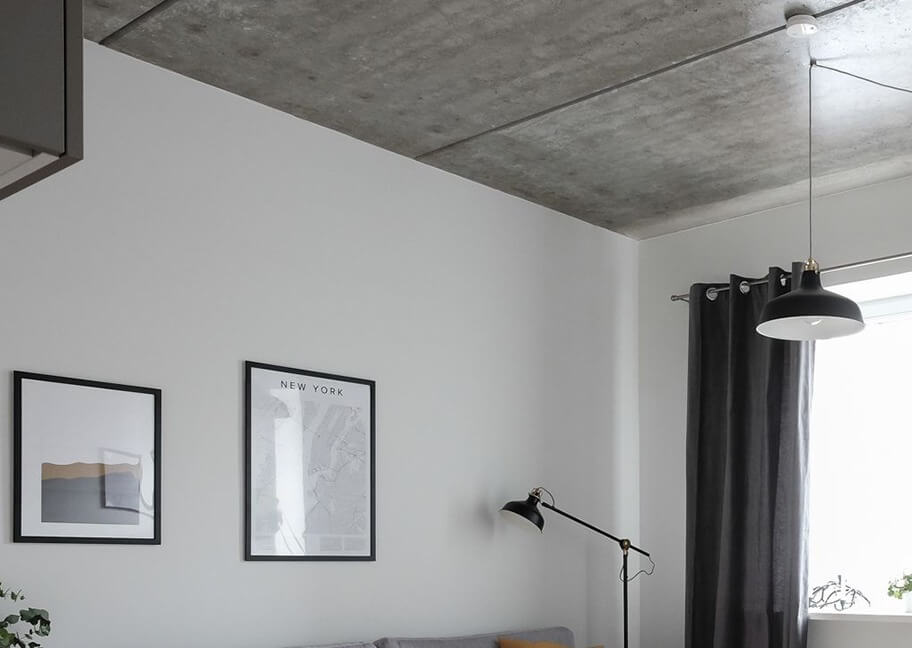 Phòng khách hiện đại với trần bê tông, đèn thả, và tranh treo tường nghệ thuật.
