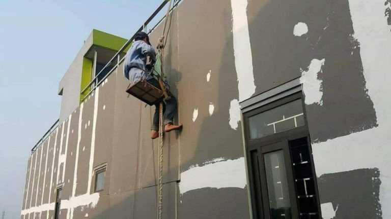 Công nhân sơn tường ngoài trời trên giàn giáo, thực hiện công việc trang trí và bảo trì tòa nhà.