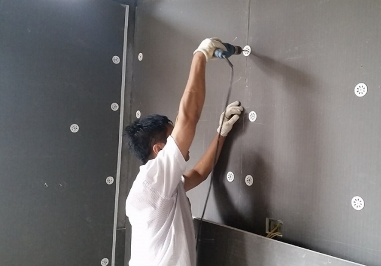 gach-mat-chong-chay Nhân viên thi công khoan tường trong công trình xây dựng, sử dụng máy khoan cầm tay, bên trong phòng.