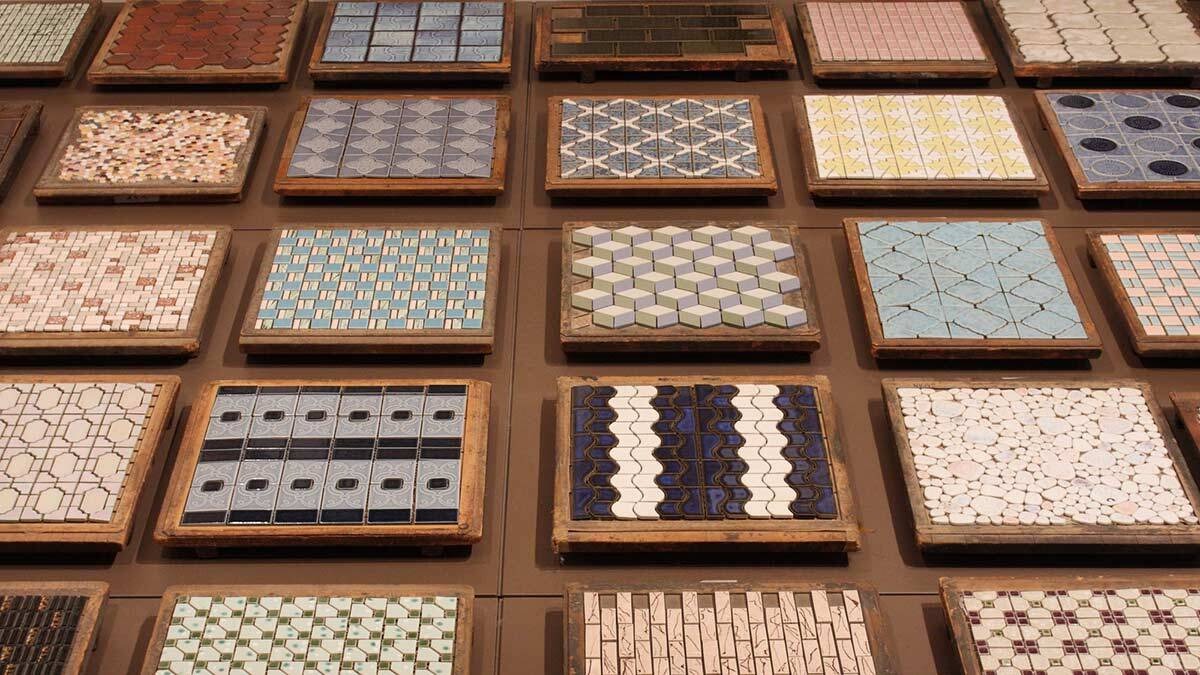 Mẫu gạch nhiều màu sắc và họa tiết độc đáo, trưng bày trên kệ, tạo cảm hứng thiết kế nội thất.