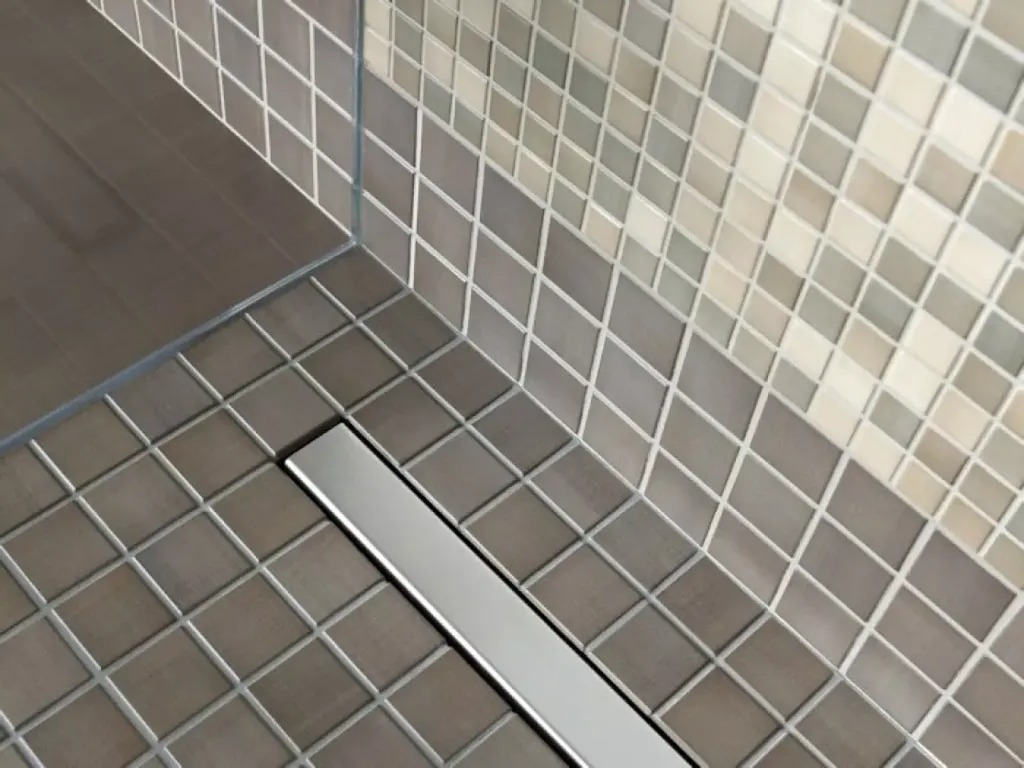 Cống thoát nước hiện đại trên sàn phòng tắm lát gạch vuông sang trọng màu xám và be.