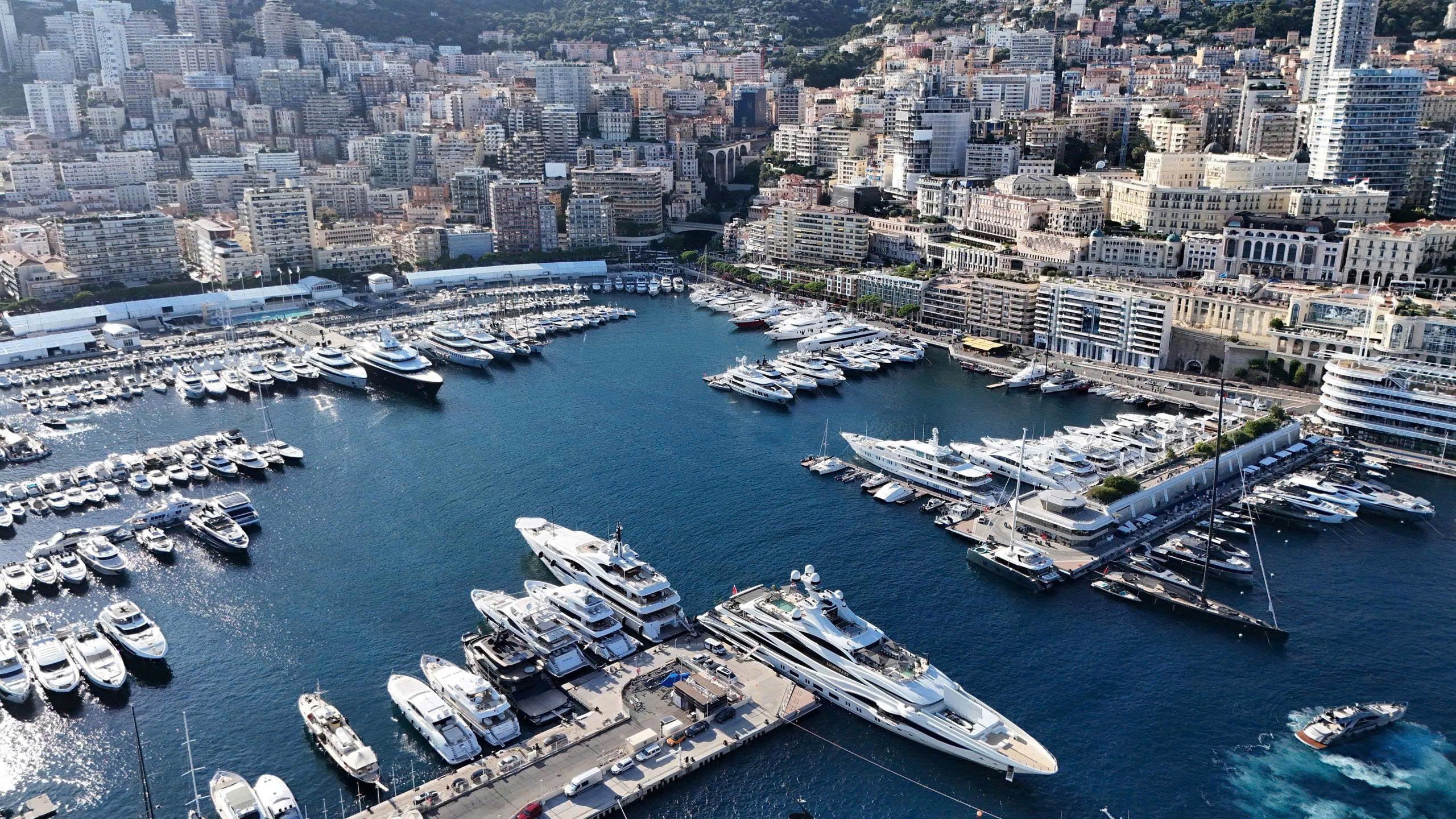 Bến du thuyền sang trọng tại thành phố biển với nhiều tàu thuyền và tòa nhà cao tầng xung quanh.